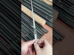 Um homem mostra um pequeno componente feito de tubo de aço carbono